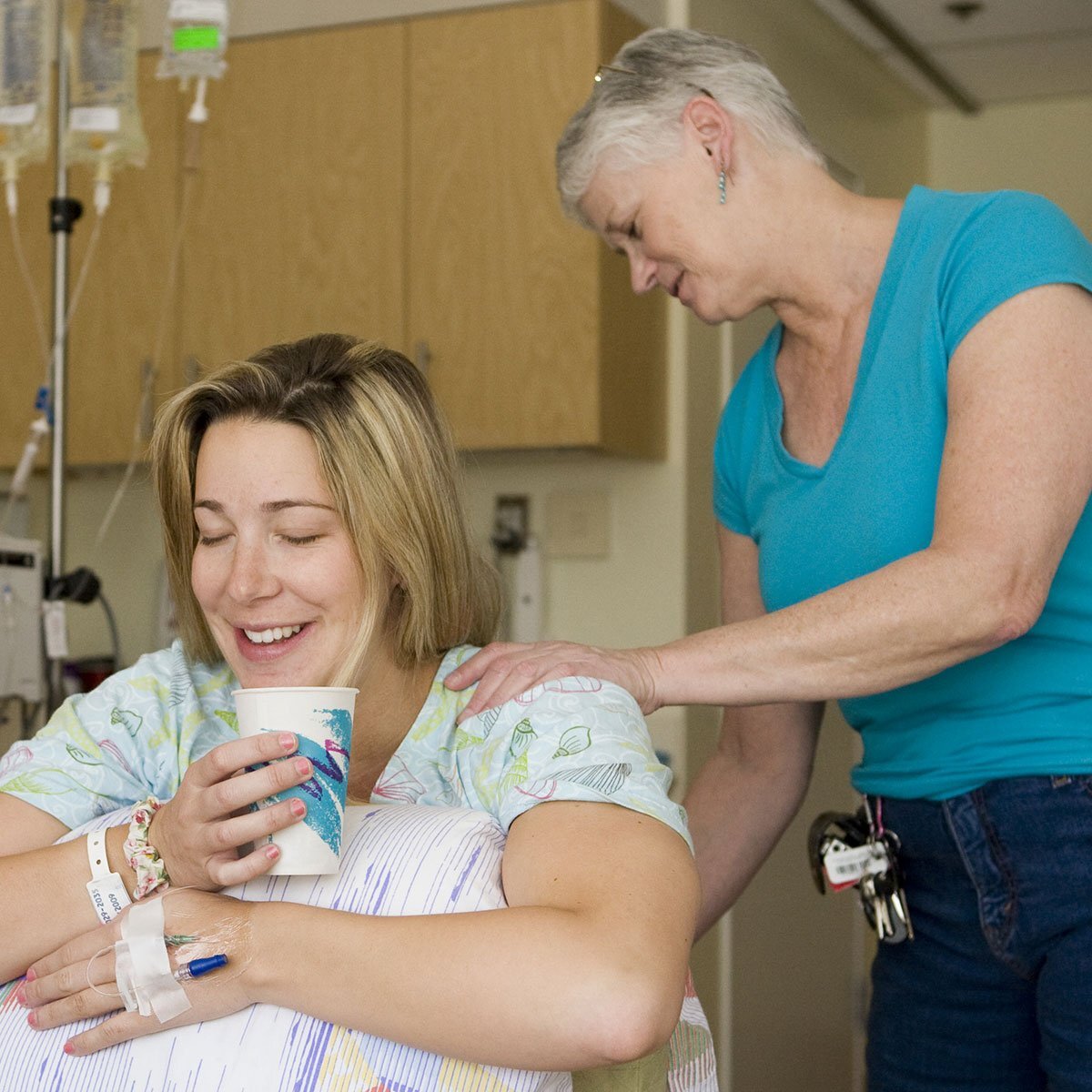 woman in labor leaning on birth ball while doula is giving her a back massage