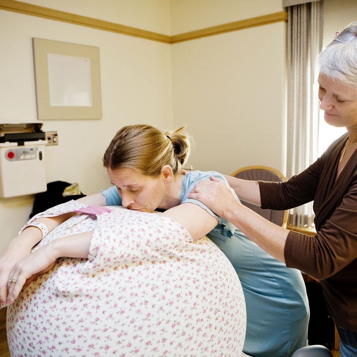 doula using birthball to help pregnant woman relax